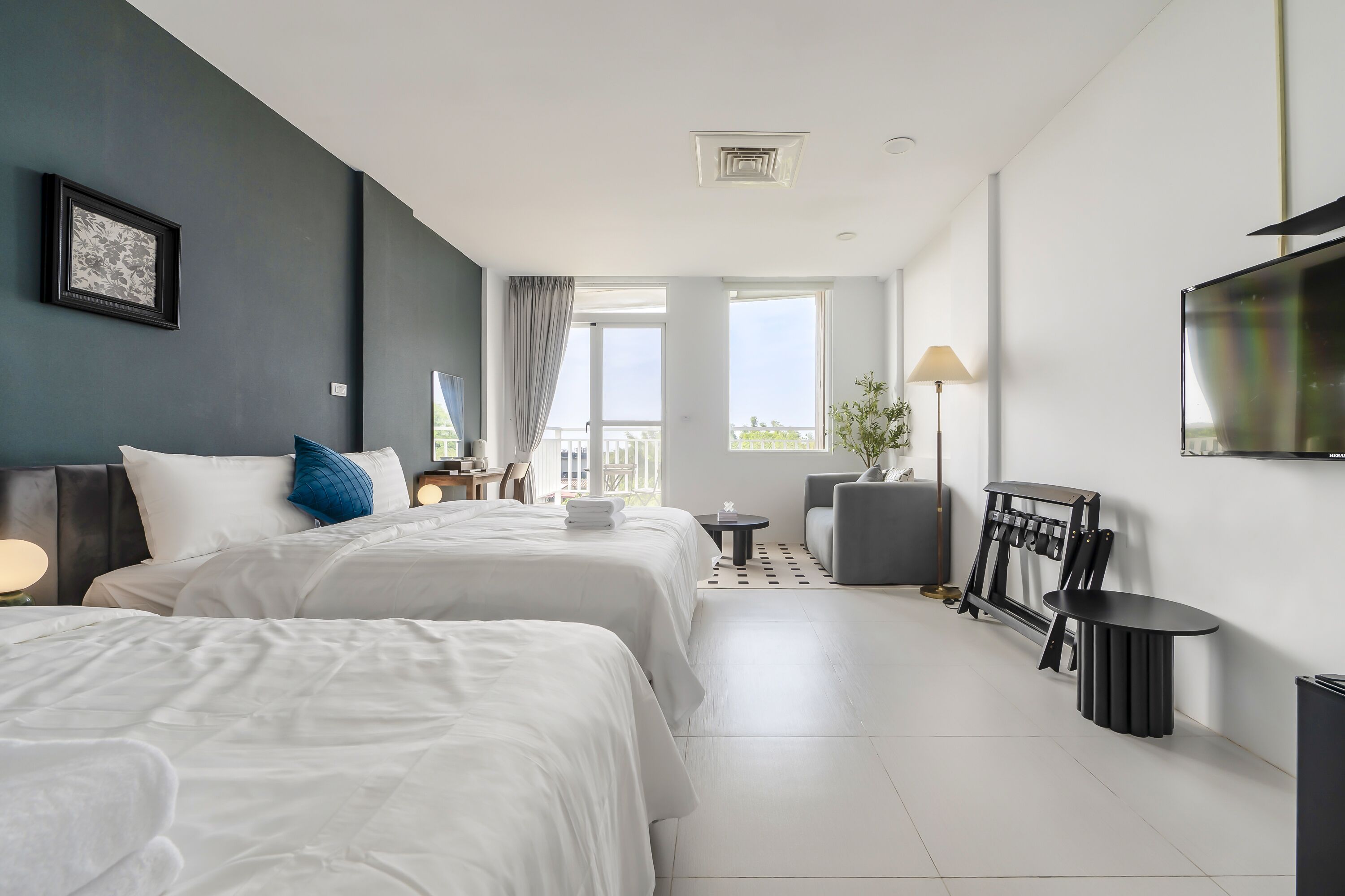 Une chambre d’hôtel avec deux lits, un bureau, une chaise, une télévision et un balcon avec vue.