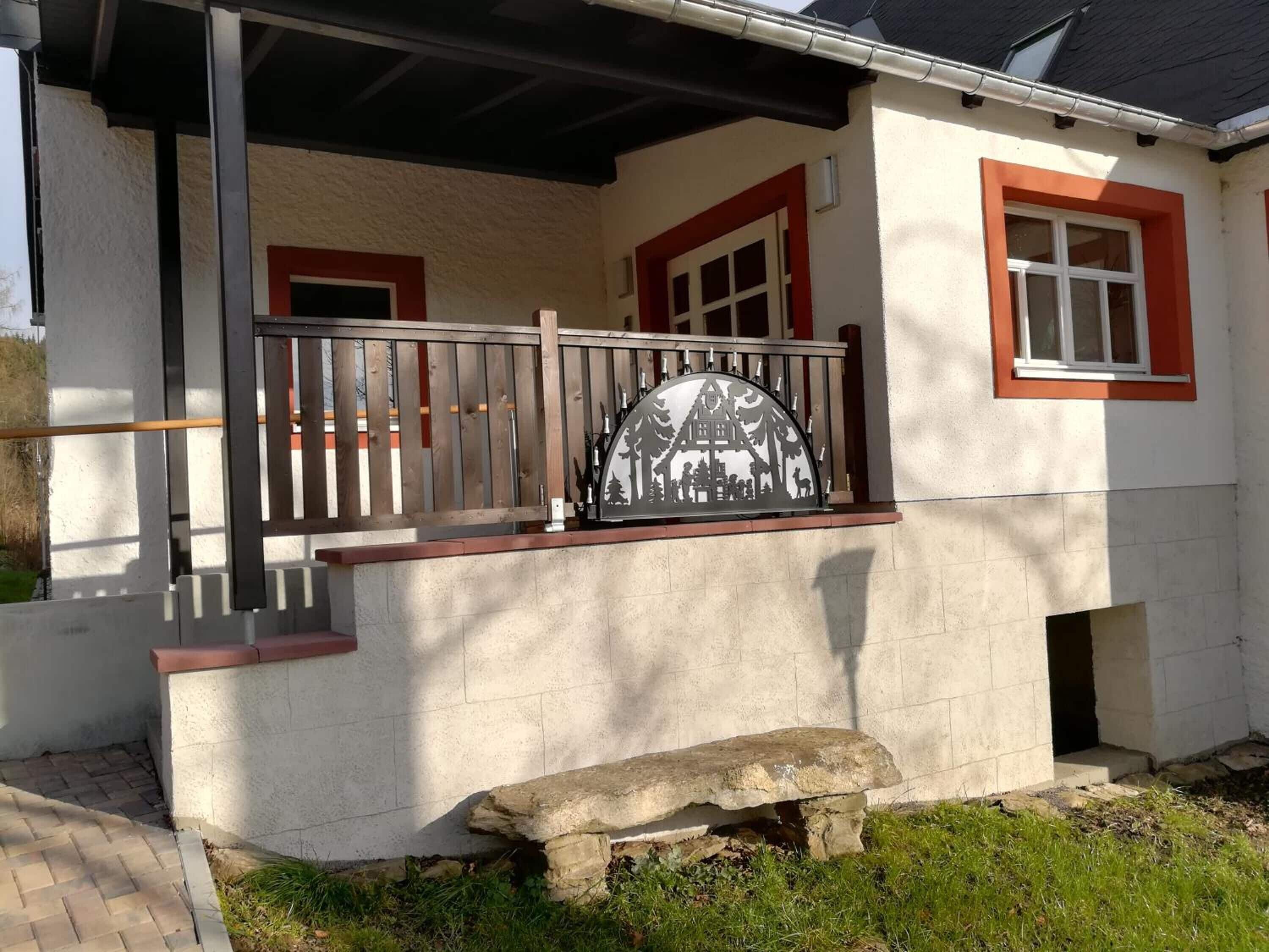 A building with a balcony, a stone bench, and a metal railing.