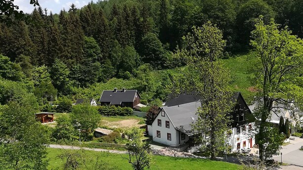 Un village rural aux maisons traditionnelles, entouré de forêts denses.