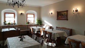 Un espace repas comprenant plusieurs tables et chaises, un lustre et des appliques murales.
