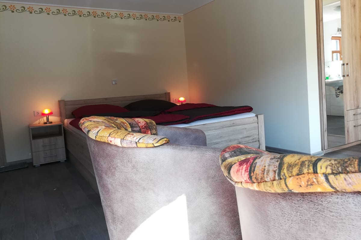 Ein Schlafzimmer mit einem Bett, zwei Nachttischen mit Lampen, einem Holzschrank und einem Spiegel.