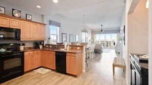 A modern kitchen with wooden cabinets, a central island, and a dining area with a view.