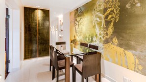 A dining area with a glass table, wooden chairs, and a large Buddha mural on the wall. - Central London Apartment, near Victoria Station (London)