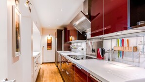 A modern kitchen with a white countertop, stainless steel appliances, and wooden flooring. - Central London Apartment, near Victoria Station (London)