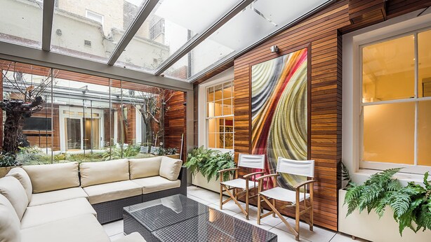 A modern living room with a glass ceiling, a sofa, a coffee table, and wooden paneling. - Central London Apartment, near Victoria Station (London)