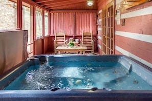 Relax in a hot tub surrounded by a rustic cabin-style setting.