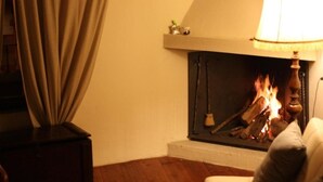 A cozy living room with a fireplace, a sofa, and a lamp. - Il Lupo Rosso (Santu Lussurgiu)
