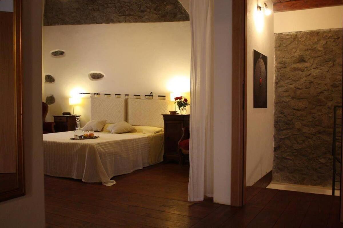 A bedroom with a bed, bedside table, and a stone wall.
