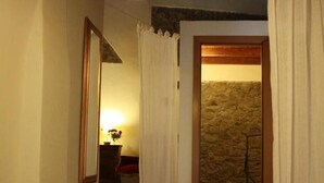 A staircase with wooden steps leading to a room with a stone wall and a door with curtains. - Il Lupo Rosso (Santu Lussurgiu)