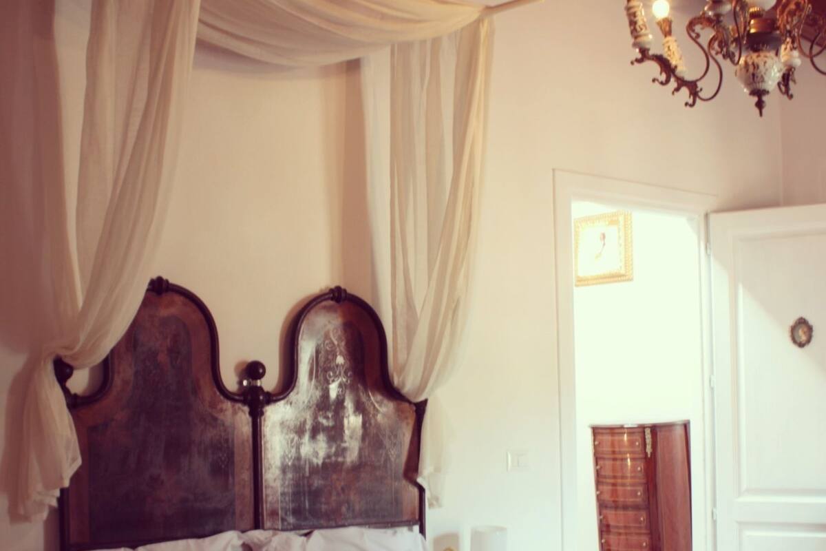 A bed with a wooden headboard, two yellow pillows, and a white bedspread.