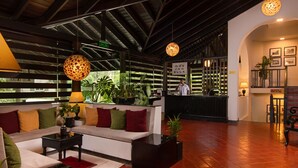 A hotel lobby with a reception desk, seating area, and potted plants. - EKHO Ella (Ella)