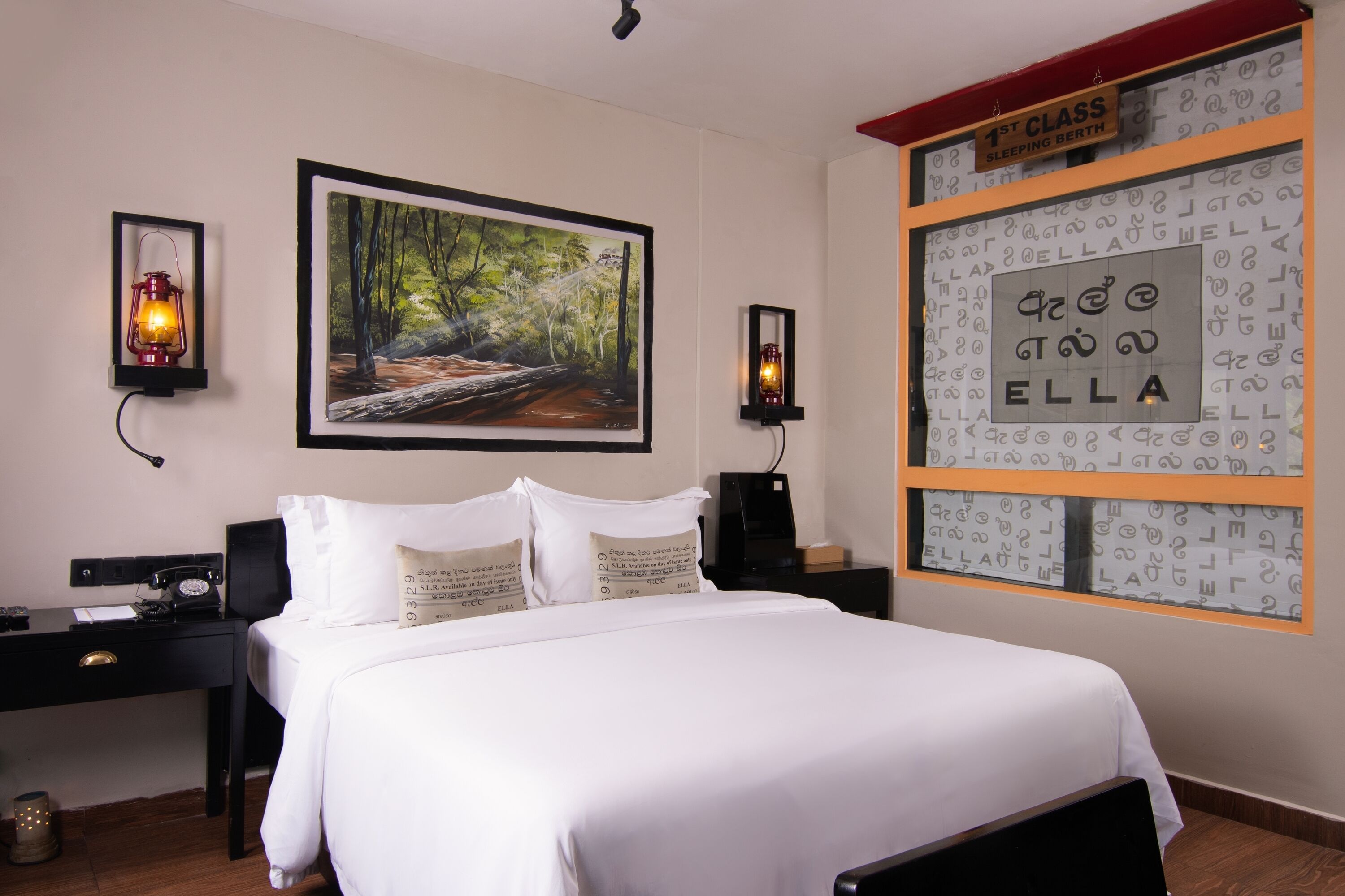 A neatly made bed with white bedding, a framed painting of a forest scene above it, and a wall with a sign reading "1st Class Sleeping Berth" and a framed nameplate with "ELLA".