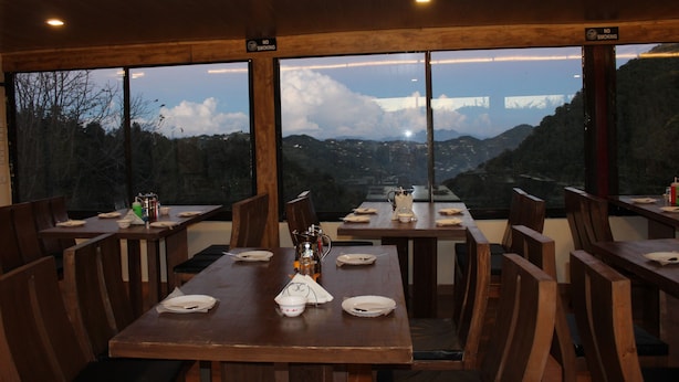 A dining area with wooden tables and chairs, a view of mountains through large windows, and a 'No Smoking' sign on the windowsill.