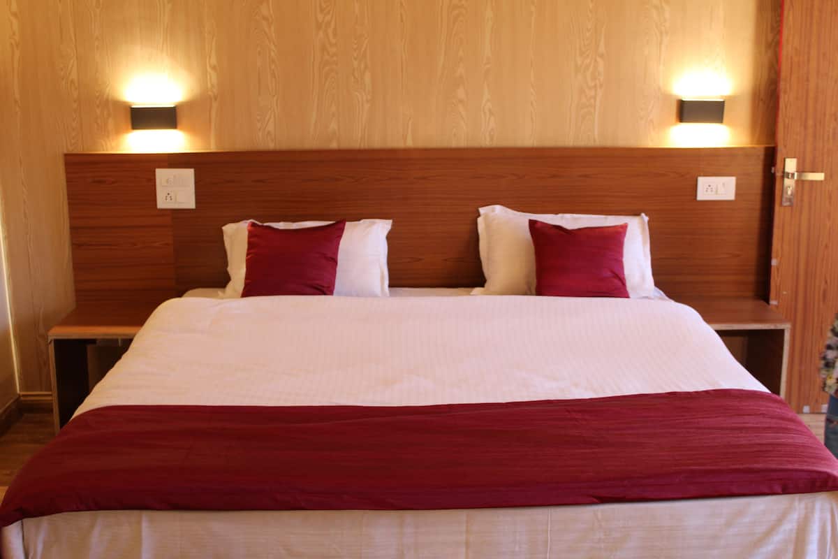 Een hotelkamer met een houten hoofdeinde, twee nachtkastjes en een bed met wit en rode beddengoed.