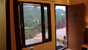 A room with a view of a red bridge and forested hills.
