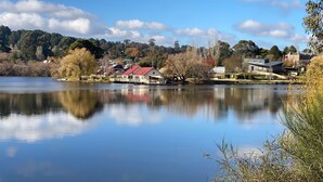 Una propiedad frente al lago con una casa de techo rojo, un muelle y un reflejo en las aguas tranquilas.