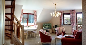 Un coin repas avec un escalier en bois, une table à manger avec des chaises, un téléviseur et un canapé rouge.
