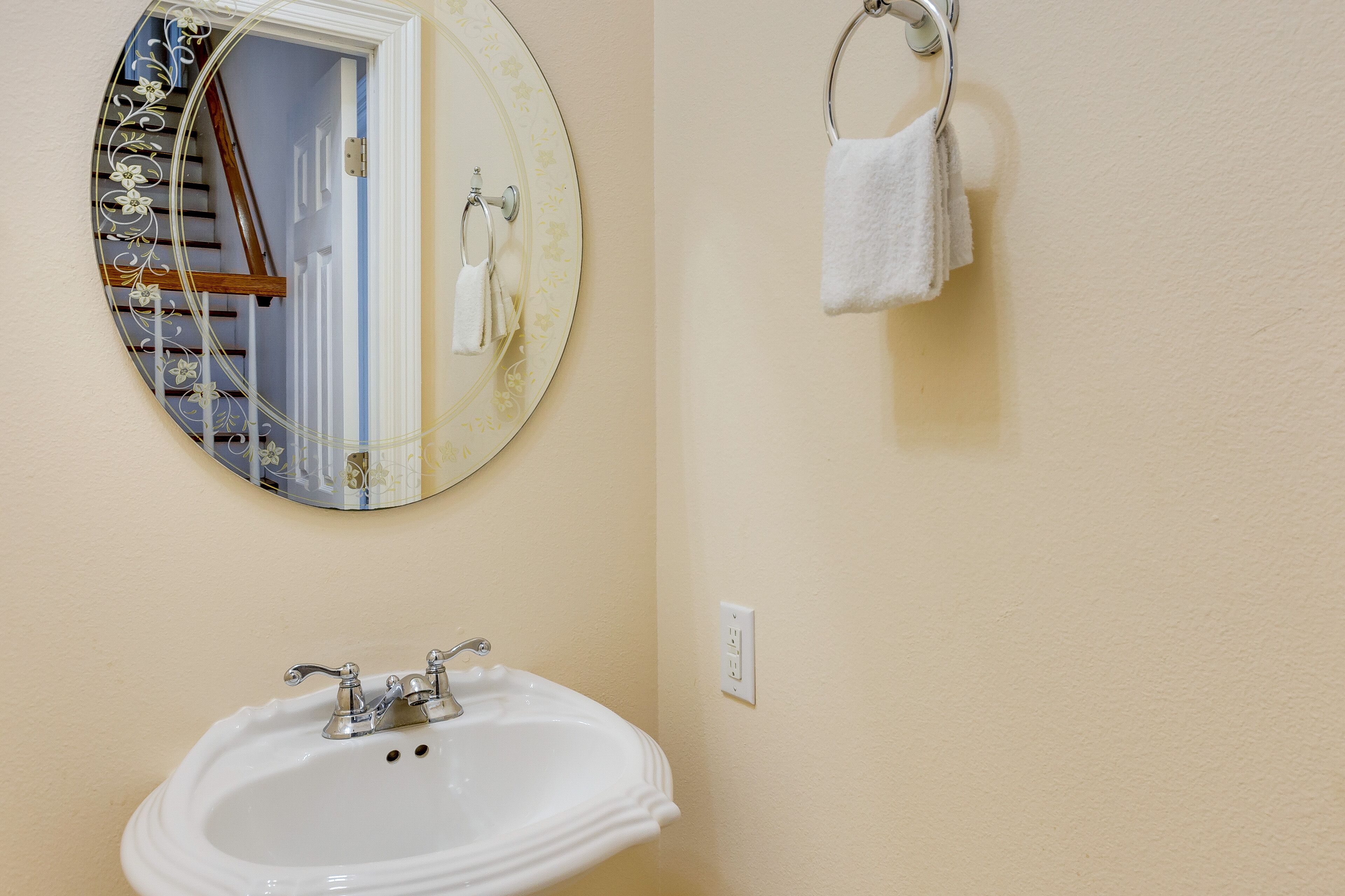 A bathroom with a round mirror, a sink, and a towel rack.