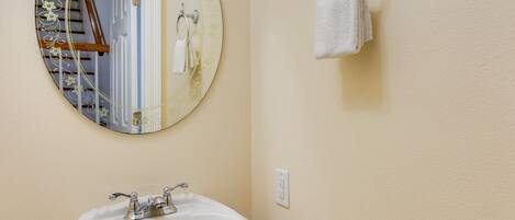 A bathroom with a round mirror, a sink, and a towel rack.