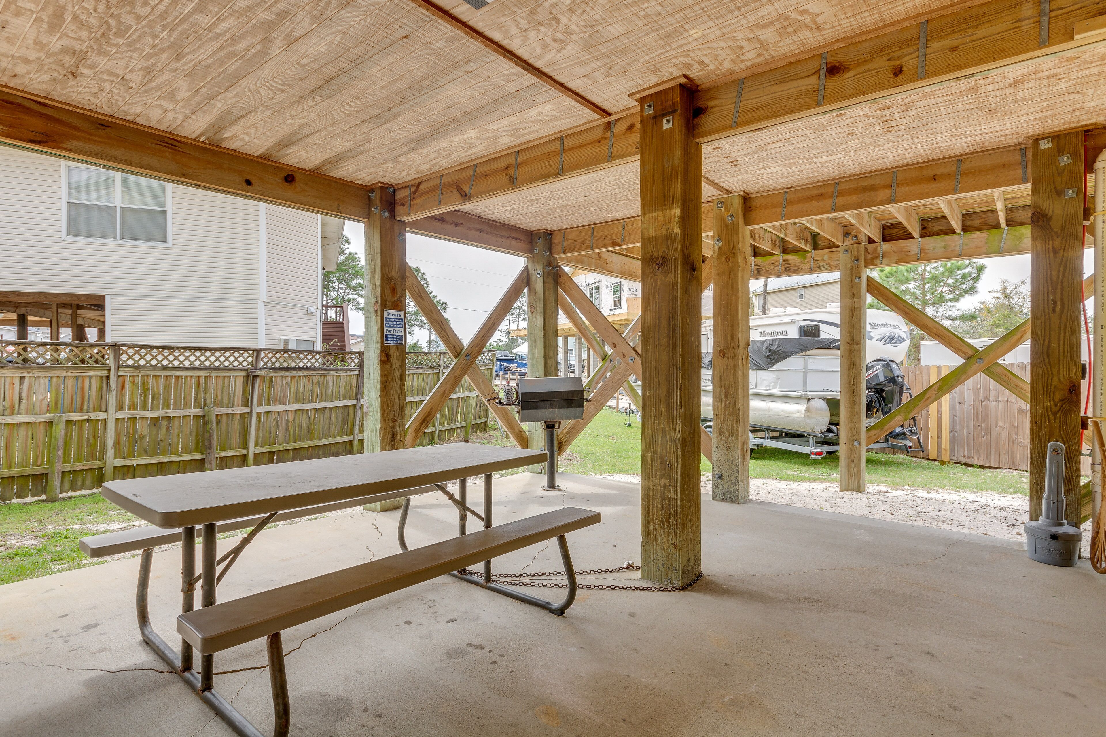 A covered picnic table with a concrete floor and wooden beams.