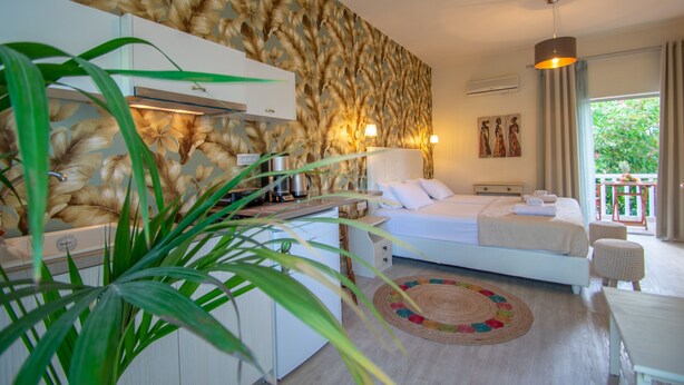 A bedroom with a bed, bedside table, lamp, and a view of the outdoors. - Villa Daizy (Zakynthos)