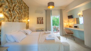 A hotel room with two beds, a desk with a laptop, a chair, and a balcony with a table and chairs. - Villa Daizy (Zakynthos)