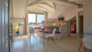 A spacious dining area with a glass table, white chairs, and a stone accent wall. - Villa Daizy (Zakynthos)