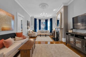 A modern living room with a sofa, coffee table, and TV stand. - Historic and Charming Brownstone (Boston)