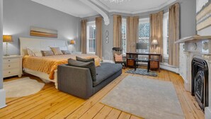 Une chambre à coucher comprenant un lit, un canapé, un bureau, une cheminée et un lustre.