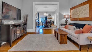 Un salon moderne avec une console en bois foncé, un canapé blanc et un grand téléviseur à écran plat.