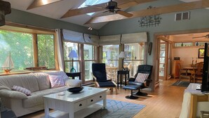 A spacious living room with a large window, a ceiling fan, and a cozy seating area with a sofa and chairs. - Eastham home near the water & bike path; large screened in porch - Pet Friendly (Eastham)
