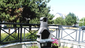 A stone outdoor grill with a metal fence in the background. - Studio Cap d'Erquy - Villas des Sables (Fréhel)