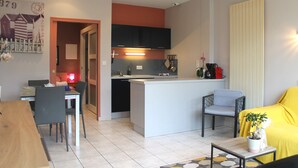 A compact living space with a kitchen, dining area, and a sofa. - Studio Cap d'Erquy - Villas des Sables (Fréhel)