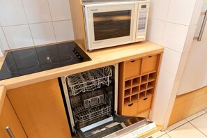 A compact kitchen with a built-in microwave, a dishwasher, and a stovetop.