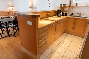 Een kleine keuken met houten kastjes, een aanrecht en een spoelbak.