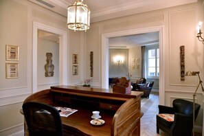 A dining area with a wooden table, chairs, a chandelier, and artwork on the walls.