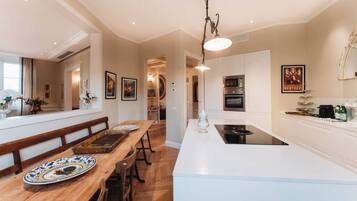 Une cuisine moderne dotée d’un îlot central, de fours encastrés et d’un coin repas avec une table et des bancs en bois.