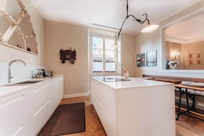 A modern kitchen with a central island, white cabinetry, a large window, and pendant lighting.