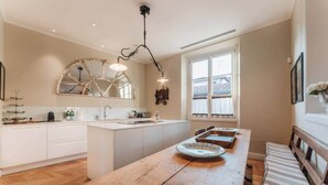 A kitchen with a wooden island, white cabinets, a large window, and a hanging light fixture. - Luxury Suite Apartment of 200sqm with terrace (Firenze)
