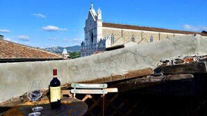 A table with a bottle of wine and a glass, overlooking a historic building with a tower. - Luxury Suite Apartment of 200sqm with terrace (Firenze)