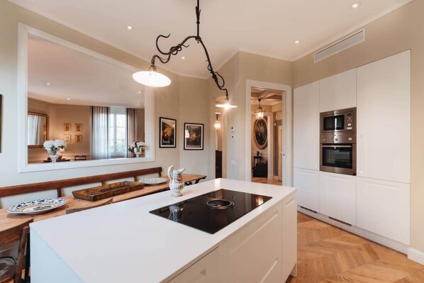 A modern kitchen with a central island, built-in oven, and pendant lighting.