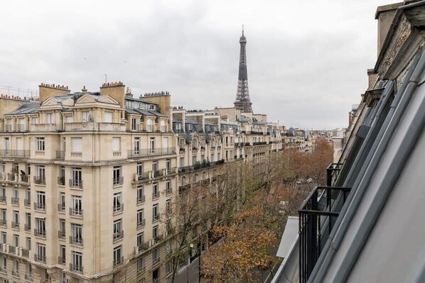 A row of classical Parisian buildings with a view of the Eiffel Tower in the background. - Coquelicot | Delightful 1 Bedroom Apt near Eiffel Tower (Paris)