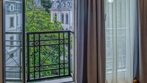 A room with a large window, a balcony with a metal railing, and a view of buildings and trees. - Venis Boutique Hotel (Bucharest)