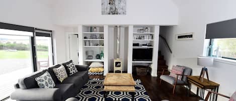 A modern living room with a grey sofa, patterned rug, and a fireplace.