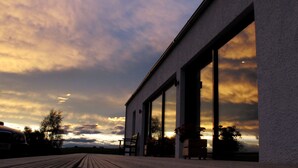 A modern building with large windows and a wooden deck. - Stunning 4 bedroom countryside retreat (Aberlour)