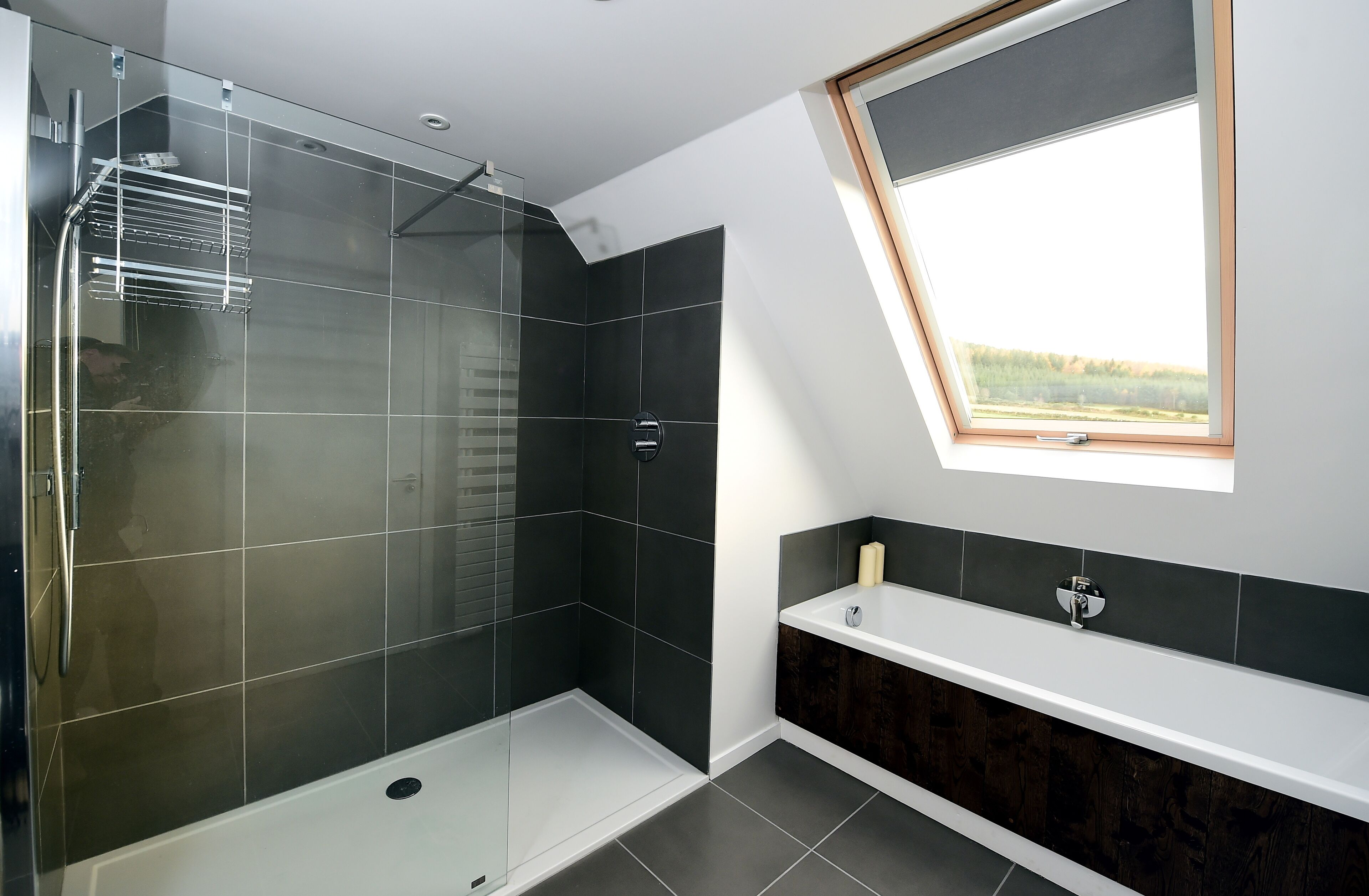 Une salle de bain moderne dotée d’une douche en verre, d’un meuble-lavabo avec un placard en bois foncé et d’un puits de lumière.