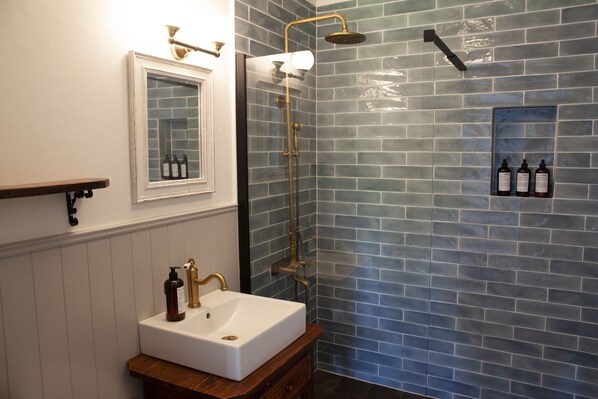 A bathroom with a white sink, brass fixtures, and a shower with a glass door.