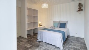 Um quarto com uma cama, mesa de cabeceira, abajur e prateleira na parede.