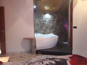 A bathroom with a stone wall, a bathtub, and a tiled floor. - Borgo Paradiso (Castel San Giorgio)