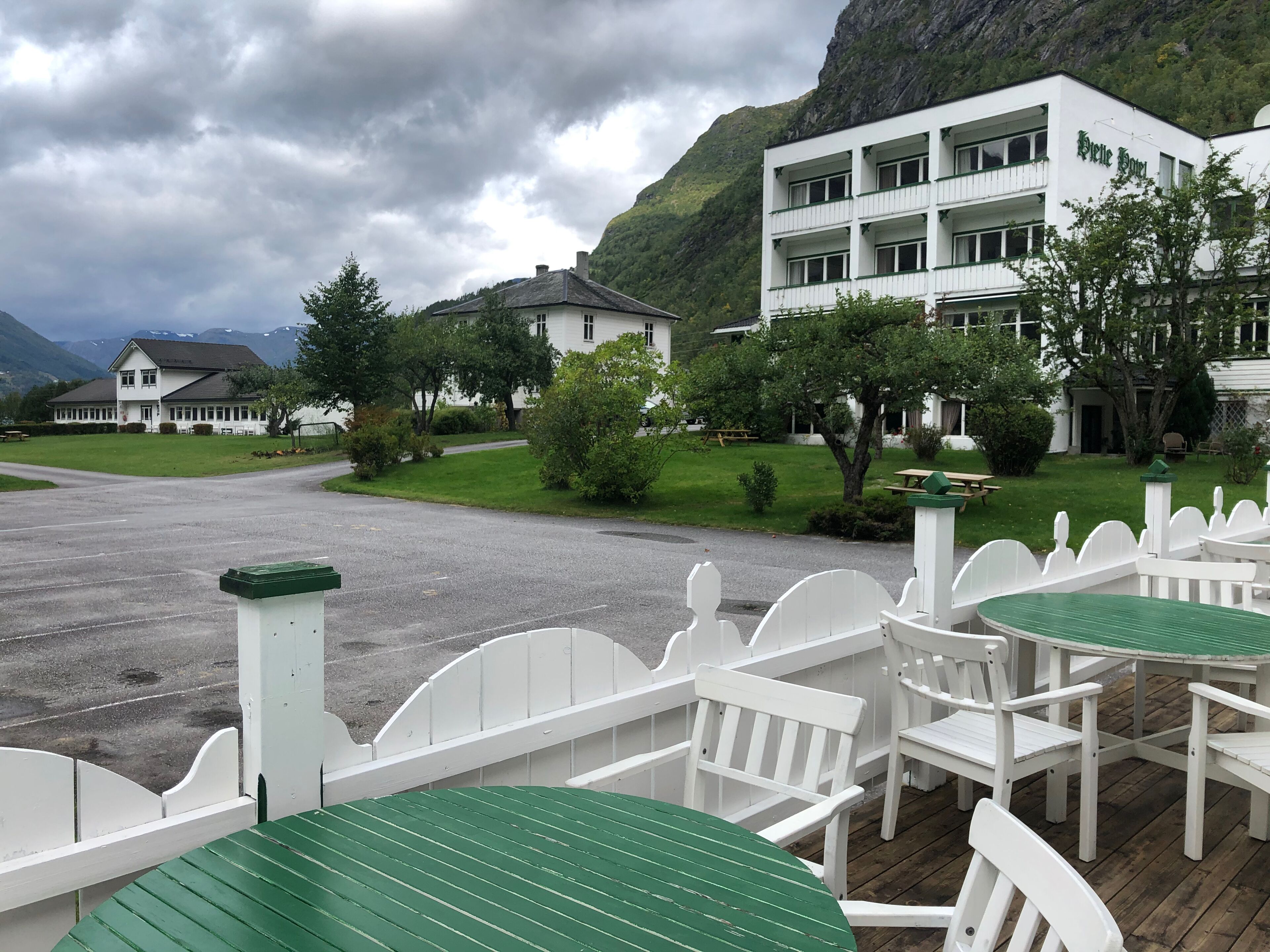 A hotel with a white exterior, multiple balconies, and a mountainous backdrop.